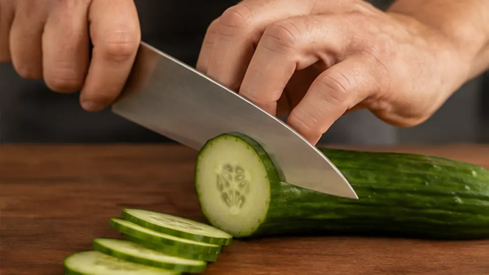 Close view of correct chef knife pinch grip and guiding hand claw technique